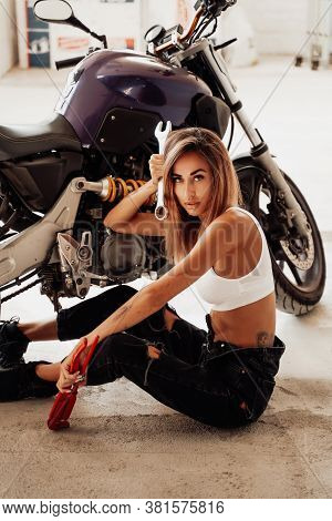 Beautiful Young Girl With Wrenches Posing In A Photo Studio With A Sports Motorcycle