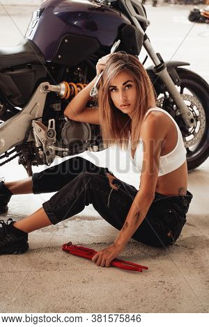 Sexy Young Girl With Wrenches Posing In A Photo Studio With A Sports Motorcycle