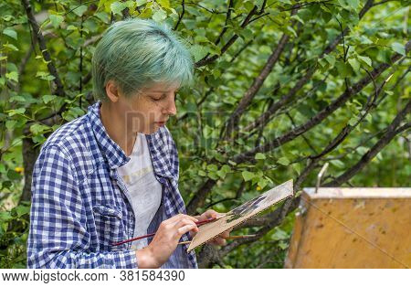 Dombay, Russia 26 July 2020: Close Up Of Young Woman Mixes Paints In Palette, Drawing Picture On Car