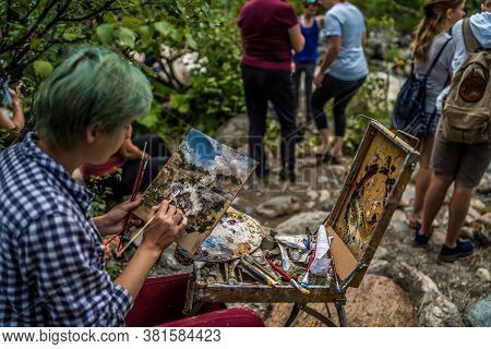 Dombay, Russia 26 July 2020: Close Up Of Young Woman Mixes Paints In Palette, Drawing Picture On Car