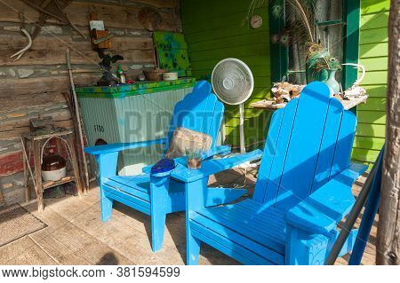 Carthage Usa - September 7 2015; Colorful Cluttered Rustic Farmhouse Porch With Bright Blue Chairs