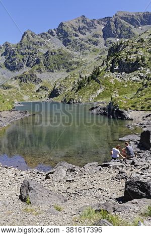 La Pra, France, August 6, 2020 : A Young Couple Of Hikers Rest For A While On The Shoreline Of A Bea