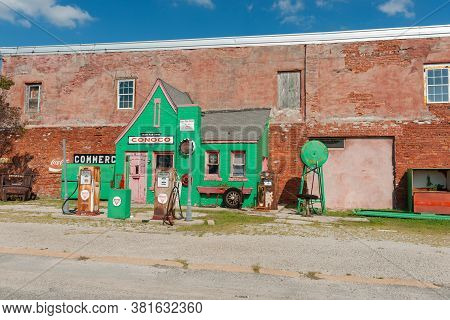 Commerce Usa - September 7 2015; Historic Green Conoco Garage Attached To Old Brick Industrial Wall 