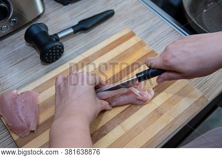 Female Hands Cut Chicken Fillet On Wooden Board With A Knife