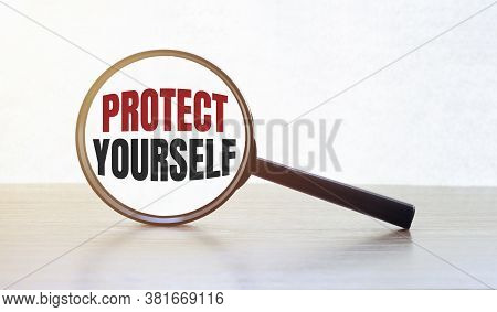 Magnifying Glass With Text Protec Yourself On Wooden Table.