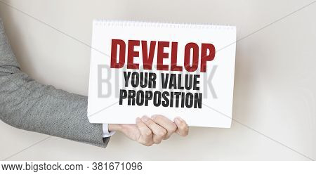Businessman Holding A Card With Text Delevop Your Value Proposition