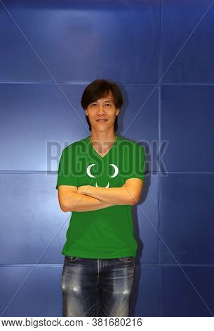 Man Wearing Ottoman Tripolitania 18th Century Flag On Shirt And Cross One's Arm On The Blue Wall Bac