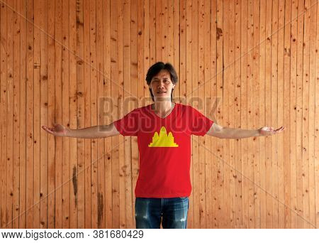 Man Wearing Democratic Kampuchea Flag Color Shirt And Standing With Arms Wide Open On The Wooden Wal