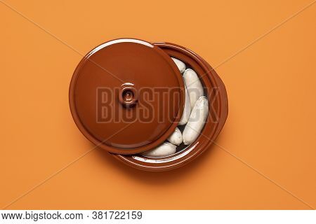 Boiled White Sausage In A Brown Pot, Isolated On Orange Background. Top View Of Bavarian Veal Sausag