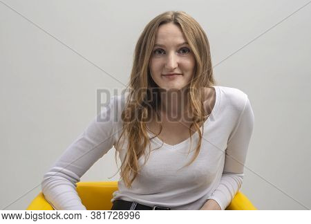 Young Caucasian Woman Interested In Coversation And Looking At Camera While Sitting In Chair, Grey B