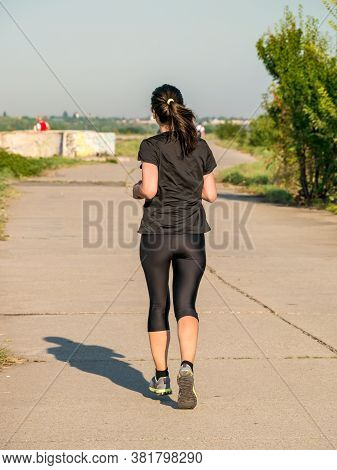 Young Girl Jogging In The Morning. Woman Working Out On Lacul Morii Or Windmill Lake In Bucharest.