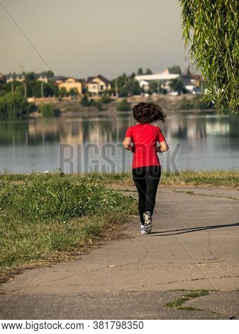 Young Girl Jogging In The Morning. Woman Working Out On Lacul Morii Or Windmill Lake In Bucharest.