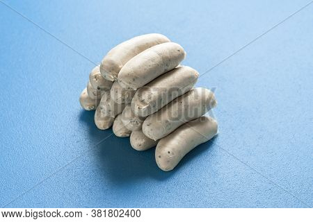 Pile Of Bavarian White Sausage Isolated On A Blue Background. Traditional German Veal Sausages Stack