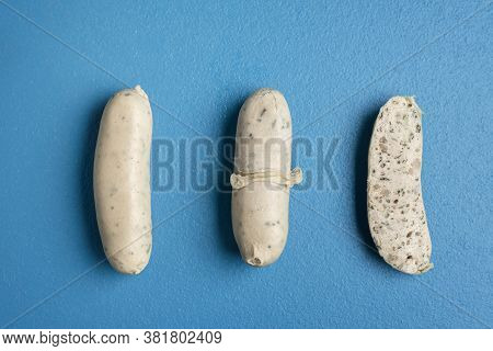 White Sausages Presentation With Peeled Skin And Wurst Section Isolated On A Blue Table. Top View Of