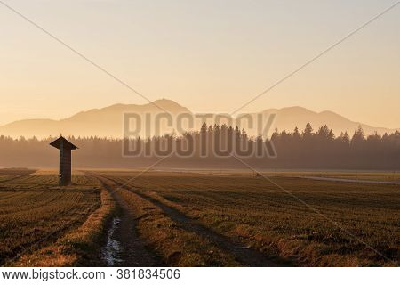 Beautiful Autumn Landscape With Meadow, Country Road And Hayrack Lit By The Gentle Light Of The Risi