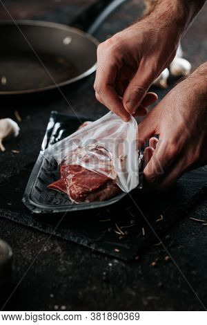 Unpackaging Sirloin Steak. Chef Preparing Fresh Meat On Dark Marble Plare.