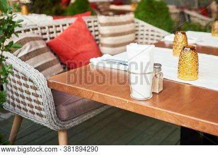 Summer Terrace Veranda Of The Cafe. Cozy Gray Wicker Chairs With Cushions, Served Tables And Green B