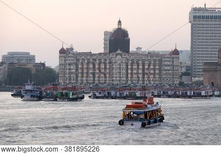 MUMBAI, INDIA - FEBRUARY 15, 2020: Taj Mahal hotel, Gateway of India and tourist boats in water of Arabian Sea in Mumbai, India