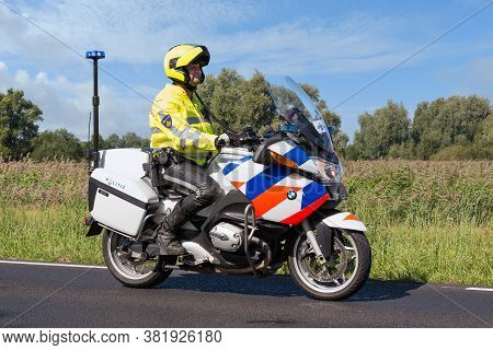 Urk, The Netherlands- September 08, 2012: Motorcycle Policeman Riding In Rural Landscape Near Urk, T