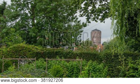 Framed View On The Brick Built Water Tower Of Kwadijk, Looking Through The Lush Greenery Of A Backya