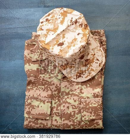 Us Army Cap On A Folded Uniform, Blue Color Background.