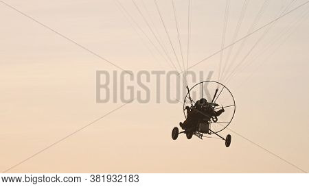 Silhouette Of The Paramotor Tandem Gliding And Flying In The Air. Copy Space High Quality Photo