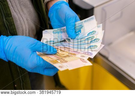 A Man Holds Russian Money In A Fan, Wearing Blue Medical Gloves. Payment For Products. Cropped Shot,