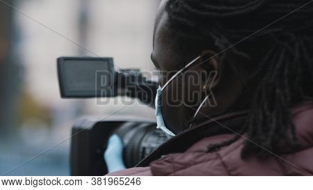 Close Up, African Black Videographer With Medikal Mask Looking Through The Viewfinder On Video Camer