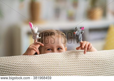 Cheerful Little Girl Is Playing Theater. Finger Puppets Put On Child's Hands. Child Laughs, Looks Ou