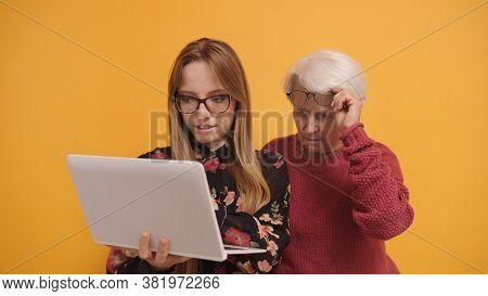 Young Woman Explaining To A Senior Lady How To Use Laptop. High Quality Photo