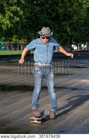 A Middle-aged Man Jumping Off Of His Skateboard Because He Lost His Balance.   Vancouver Bc Canada