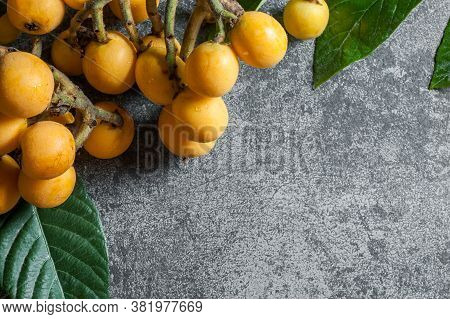 Fresh Ripe Loquat Japanese Medlar Fruit With Branch And Leaf On Rustic Background, Malta Plum, Summe