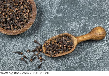 Close Up Glass Bottle Of Clove Oil And Cloves In Wooden Spoon On Wooden Table. Essential Oil Of Clov