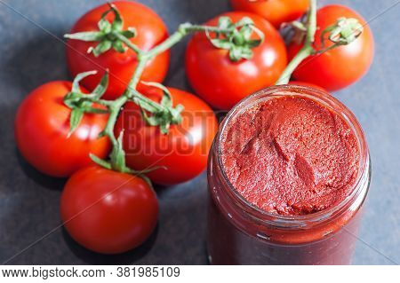 Tomato Paste In Wooden Spoon And Ripe Fresh Grape Tomatoes On Wooden Background. Cherry Tomatoes. To