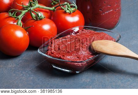 Tomato Paste In Wooden Spoon And Ripe Fresh Grape Tomatoes On Wooden Background. Cherry Tomatoes. To