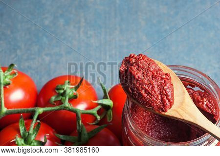 Tomato Paste In Wooden Spoon And Ripe Fresh Grape Tomatoes On Wooden Background. Cherry Tomatoes. To