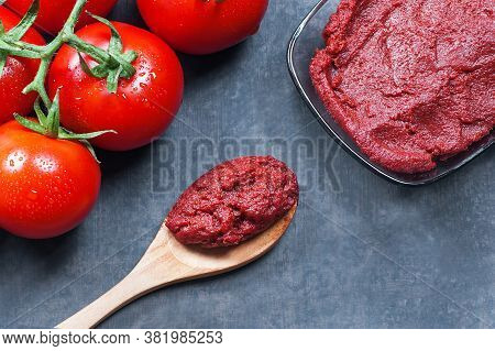 Tomato Paste In Wooden Spoon And Ripe Fresh Grape Tomatoes On Wooden Background. Cherry Tomatoes. To