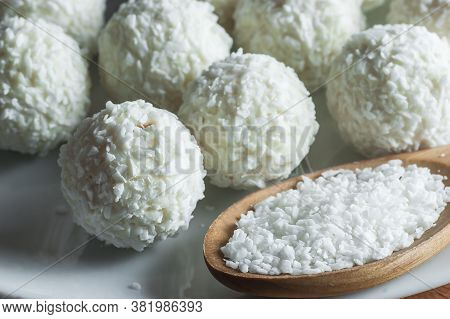 White Chocolate Ball Candy With Coconut Topping And Coconuts In Wooden Spoon. Coconuts Pastry Concep
