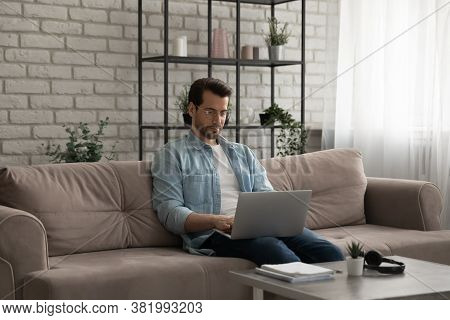Caucasian Man Sit On Couch Working On Laptop At Home