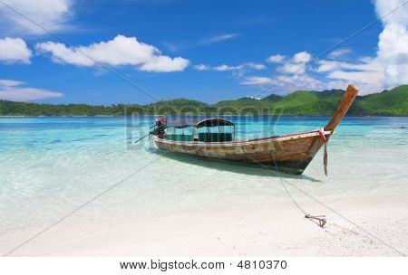 Longtail Boat dans le magnifique lagon près de plage de sable blanc