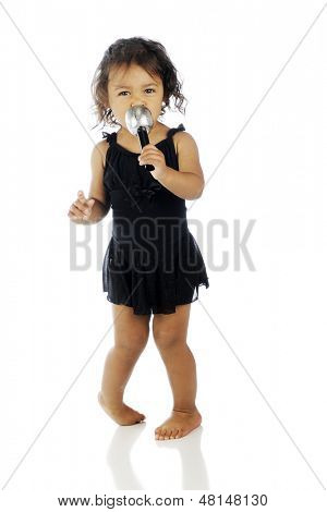 Ein adorable Toddler Performer singen in ein Mikro, während Sie ihr Kleid Tanz tanzen.  Auf einem weißen bac