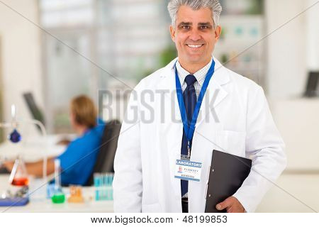 pesquisador sênior do laboratório segurando uma prancheta a sorrir