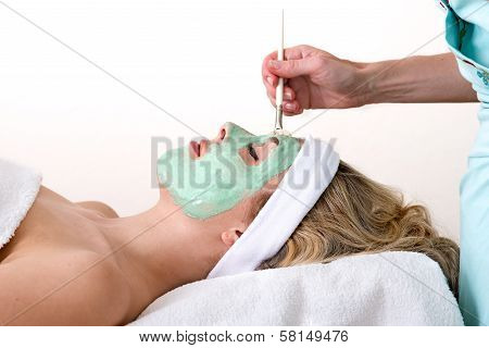 Beautician Applying Green Facial Mask On A Woman.