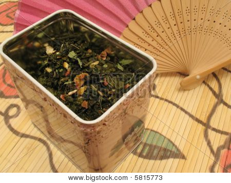 Green fruit tea in tin and Chinese fan