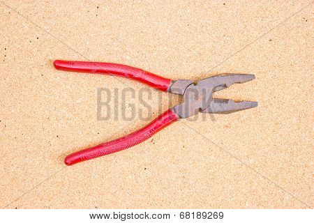 Old Red Opened Jaw Pliers On Corkboard.