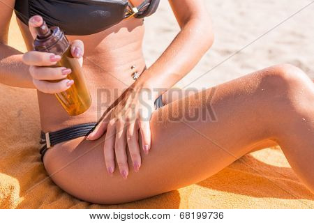 Sensuous slim woman applying suntan oil