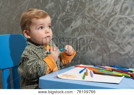 Child Sitting At A Table Drawing With Colored Markers