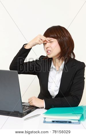 studio portrait of young Japanese businesswoman suffers from Asthenopia
