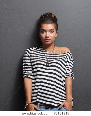 A young woman standing, isolated on graybackground.