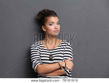 A young woman standing, isolated on graybackground.